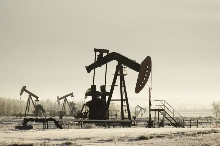 history of oil - field with oil pump jacks surrounded by greenery under sunlight